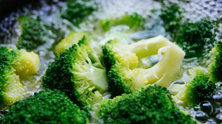 Broccoli in cottura con coperchio e fetta di pane imbevuta di aceto sopra per evitare odori.